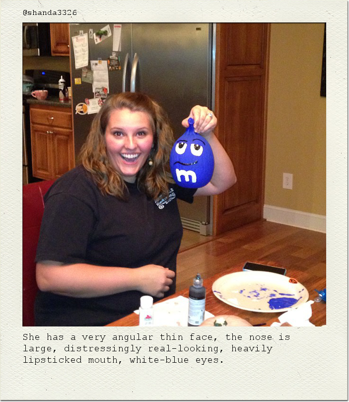 She has a very angular thin face, the nose is large, distressingly real-looking, heavily lipsticked mouth, white-blue eyes.